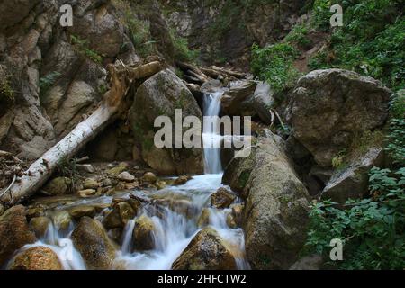 Im Sommer ein kleiner Wasserfall zwischen den Felsen in der Bergschlucht`s Monks Stockfoto